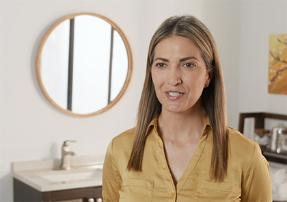 A young woman sitting inside in front of a sink and mirror